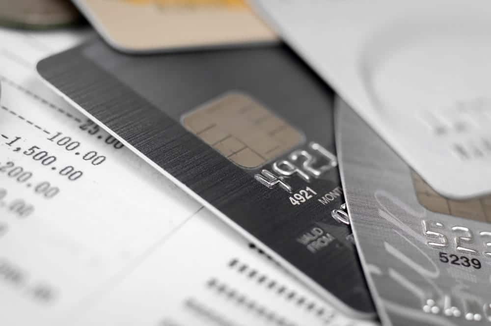 Image is of credit cards resting on billing statements, concept of credit card debt and financial obligations after divorce.