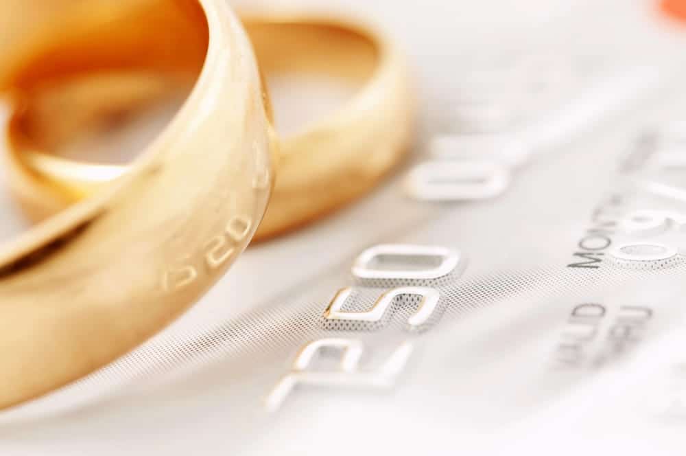 Image is of wedding rings placed near a credit card, concept of credit card debt and financial issues following divorce.