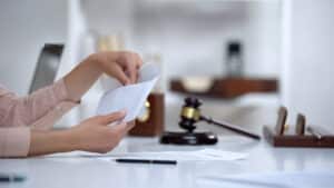 Image is of a person reviewing financial documents at a desk, concept of financial disclosure in a divorce settlement.