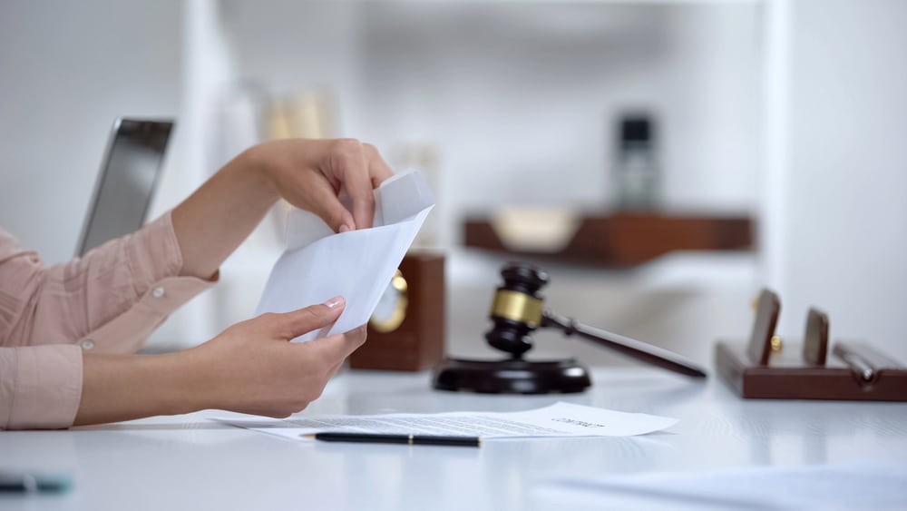 Image is of a person reviewing financial documents at a desk, concept of financial disclosure in a divorce settlement.