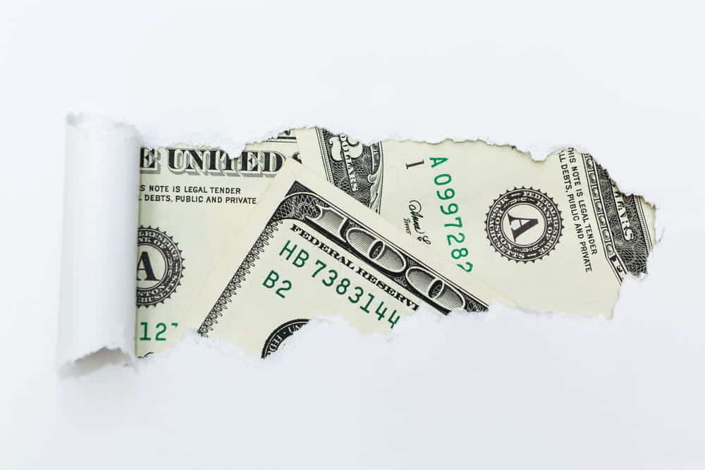 Image is of cash concealed behind torn paper, concept of hidden income affecting a divorce settlement.