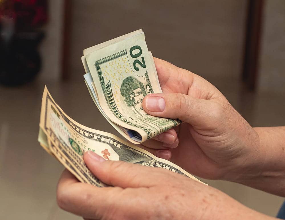 Image is of a person counting cash, concept of legal separation attorney helping spouses address financial support and household expenses.