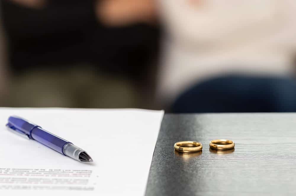 age is of wedding rings beside legal documents, concept of legal separation attorney preparing separation agreements and related legal paperwork.