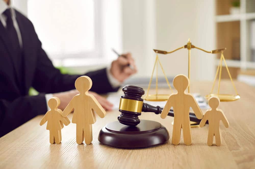 Image is of family figures beside a judge's gavel, concept of modifications of parenting plans lawyer handling parenting plan changes through the court process.