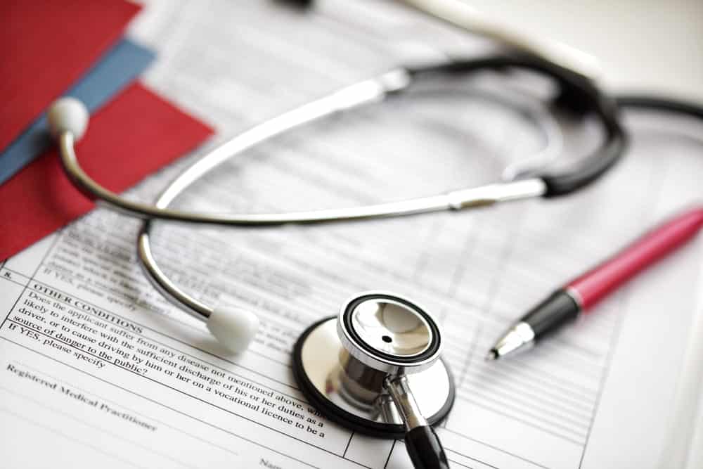 Image is of medical forms with a stethoscope and pen, concept of updating healthcare documents during estate planning in Franklin after divorce.
