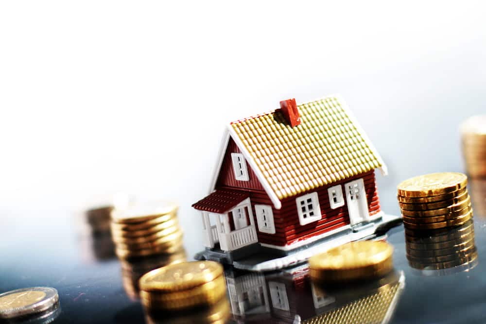 Image is of a model home surrounded by coins, concept of reviewing real estate and financial assets during estate planning in Franklin after divorce.