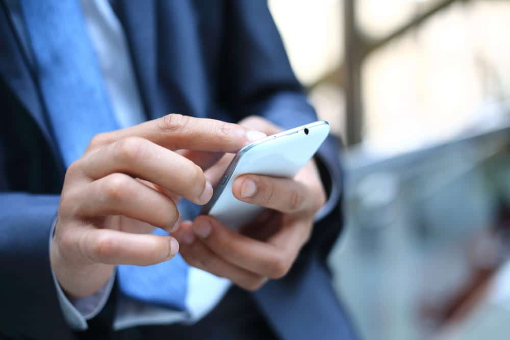 Image is of a person using a smartphone, concept of text messages documenting co-parenting mistakes.
