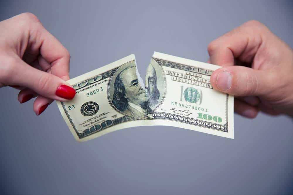 Image is of two people dividing money, concept of dividing funds in a join bank account during divorce