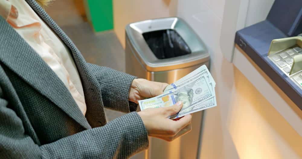 Image is of a person withdrawing cash, concept of accessing funds from a join bank account during divorce